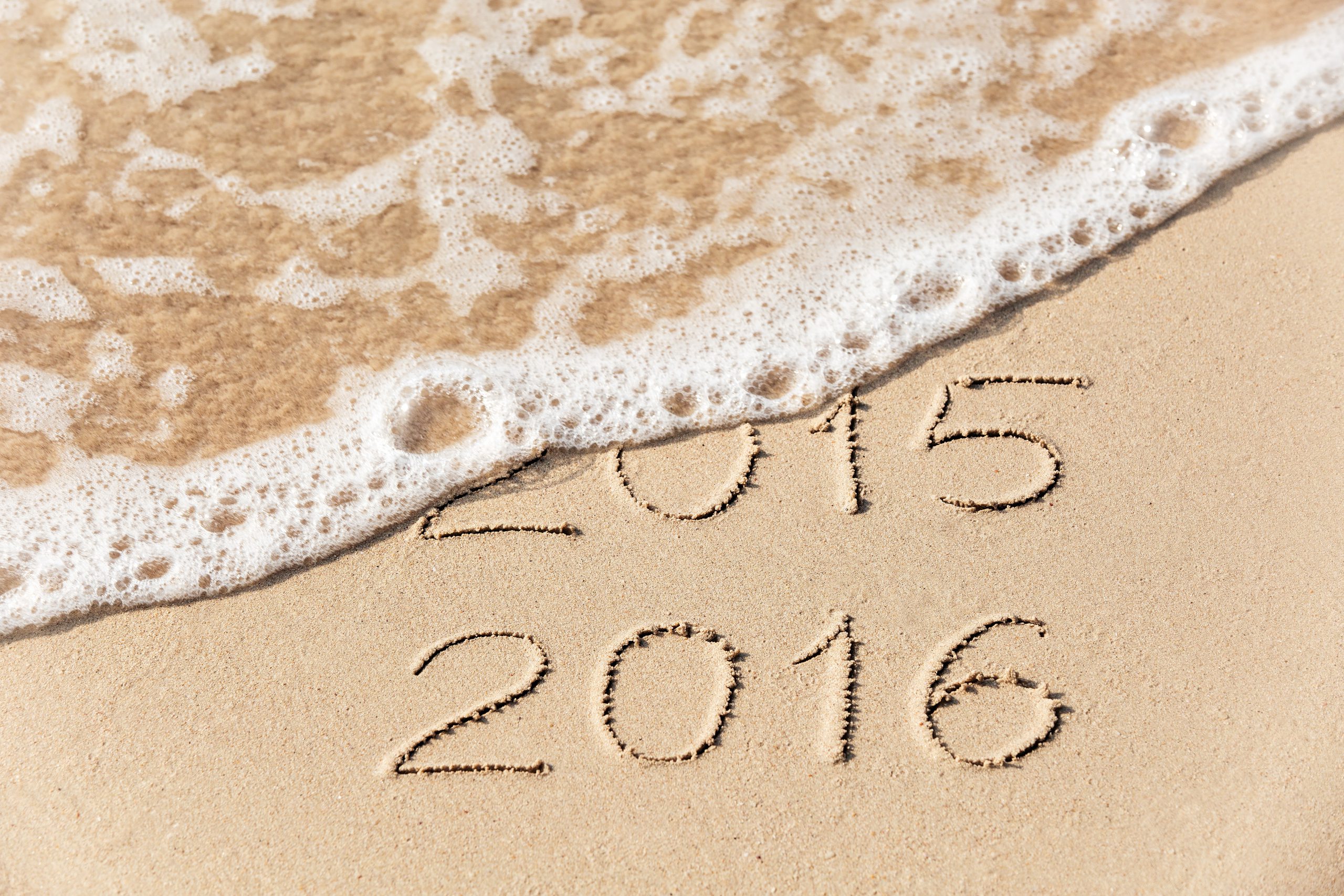 2015 2016 inscription written in the wet yellow beach sand being